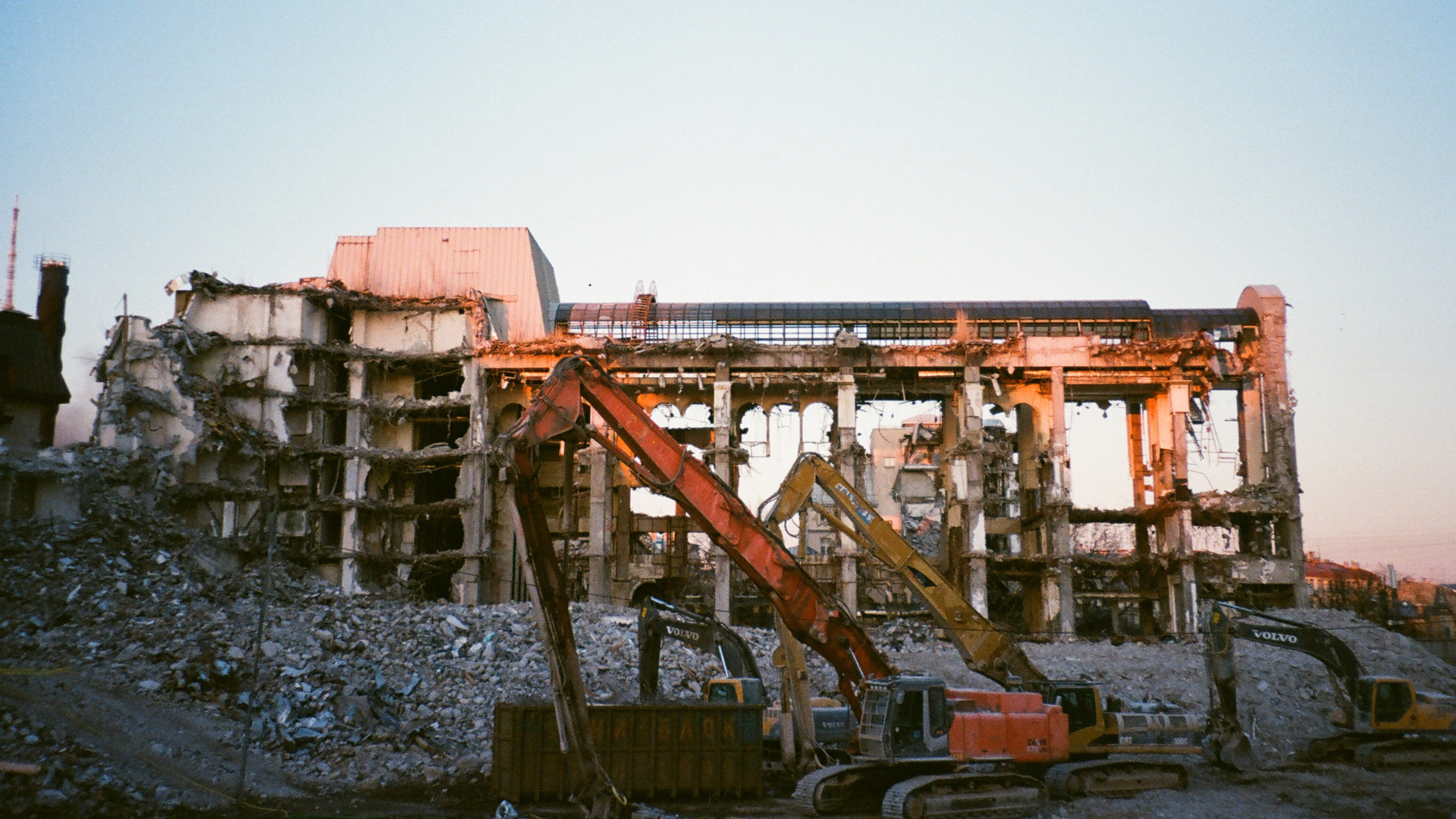 Rückbau eines Industriegebäudes mit schwerem Gerät Abbruch eines mehrstöckigen Industriegebäudes mit mehreren Baggern und schwerem Gerät bei Sonnenuntergang.
